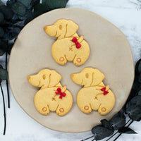 Smiling Dachshund Butt cookies with pink royal icing hind paw pads and red fondant ribbon on the tails