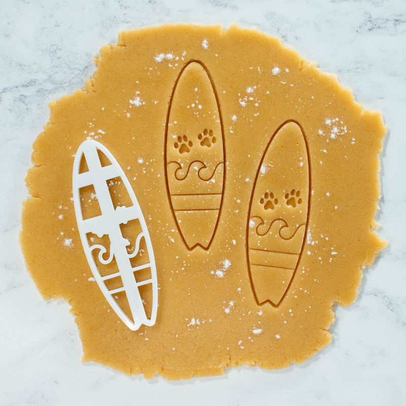 bakerlogy surfboard with paw prints cookie cutter and cookies cutout dough