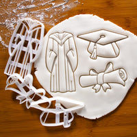 set of 3 graduation themed cookie cutters, featuring a graduation gown, a graduate cap and a scroll