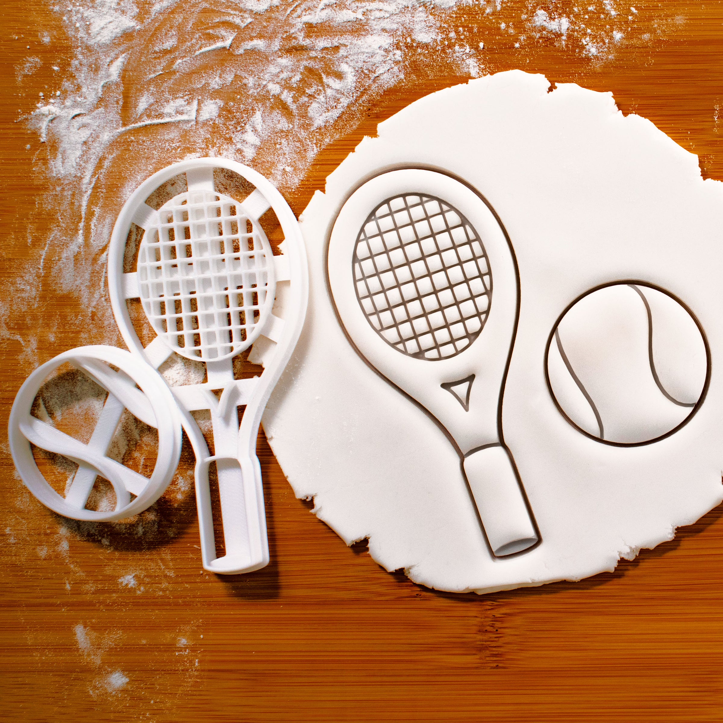 set of tennis racket and tennis ball cookie cutters pressed on fondant