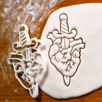 dagger in anatomical heart cookie cutter pressed on white fondant