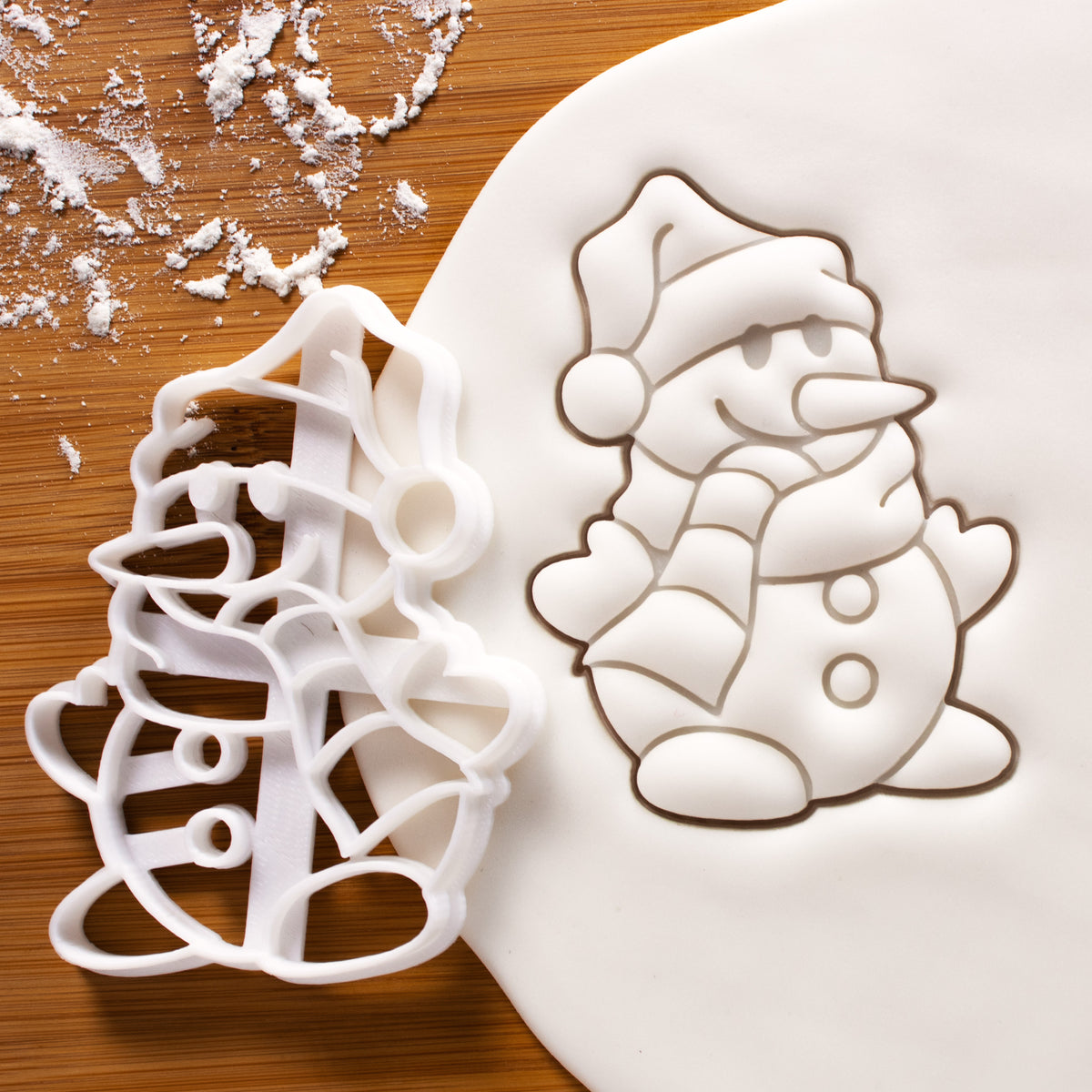 Snowman cookie cutter pressed on white fondant